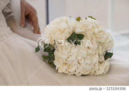 Elegant Bridal Bouquet and Dress Detail Reflecting Wedding Day Sophistication in a Brightly Lit Interior Setting Elegant Bridal Bouquet and Dress Detail Reflecting Wedding Day Sophistication in a Brightly Lit Interior Setting 125284306