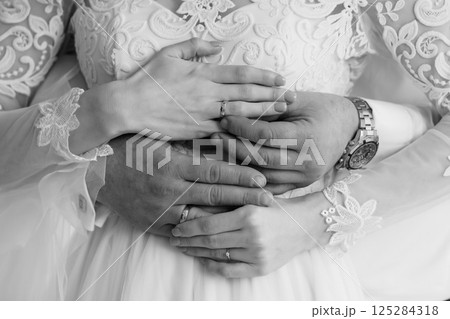 Intimate Wedding Moment: Hands Interlocked with Rings Symbolizing Love and Commitment in a Black and White Portrait 125284318