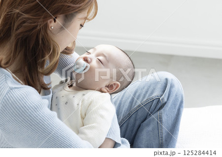 赤ちゃんを抱っこする可愛いママ 125284414