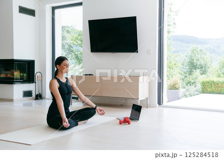 Young Beautiful Female Exercising, Stretching and Practising Yoga with Trainer via Video Call Conference in Bright Sunny House. Healthy Lifestyle, Wellbeing and Mindfulness Concept. Young Beautiful Female Exercising, Stretching and Practising Yoga with Trainer via Video Call Conference in Bright Sunny House. Healthy Lifestyle, Wellbeing and Mindfulness Concept. 125284518