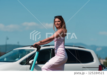 Elegant woman in a pink dress and sunglasses riding an electric scooter through the sunny city streets, embracing the freedom and style of a perfect urban adventure. Elegant woman in a pink dress and sunglasses riding an electric scooter through the sunny city streets, embracing the freedom and style of a perfect urban adventure. 125284521
