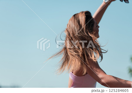 An elegant, stunning woman in a pink dress and sunglasses strikes a confident pose next to her electric scooter, radiating style and sophistication in the vibrant urban environment. An elegant, stunning woman in a pink dress and sunglasses strikes a confident pose next to her electric scooter, radiating style and sophistication in the vibrant urban environment. 125284605