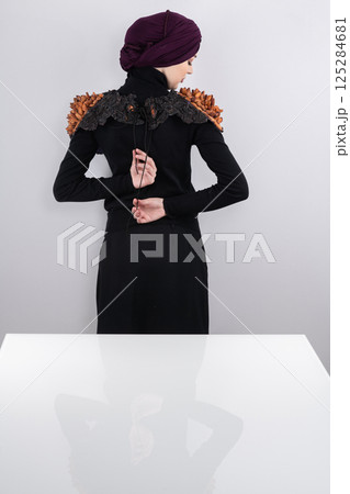 A stylish Muslim woman in a hijab presents her innovative handmade fashion accessory crafted from dried plums in a professional studio. A stylish Muslim woman in a hijab presents her innovative handmade fashion accessory crafted from dried plums in a professional studio. 125284681