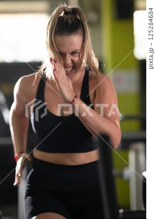 Woman Running on Treadmill in Gym.A fit woman wearing a purple sports outfit is running on a treadmill in a gym. She has a focused yet relaxed expression, with gym equipment and a warm light in the Woman Running on Treadmill in Gym.A fit woman wearing a purple sports outfit is running on a treadmill in a gym. She has a focused yet relaxed expression, with gym equipment and a warm light in the 125284684