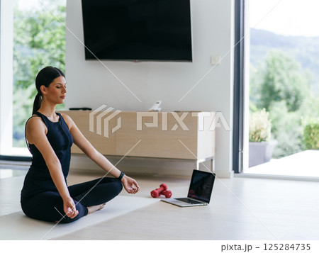 Young Beautiful Female Exercising, Stretching and Practising Yoga with Trainer via Video Call Conference in Bright Sunny House. Healthy Lifestyle, Wellbeing and Mindfulness Concept. Young Beautiful Female Exercising, Stretching and Practising Yoga with Trainer via Video Call Conference in Bright Sunny House. Healthy Lifestyle, Wellbeing and Mindfulness Concept. 125284735