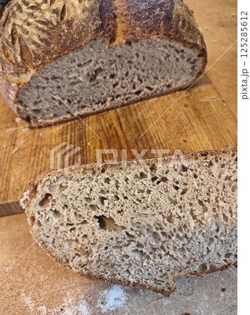freshly cut artisanal sourdough bread showing crumb and texture on a rustic wooden surface 125285612