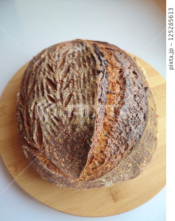 freshly baked artisanal sourdough bread with rustic crust cooling on a wooden surface side view 125285613