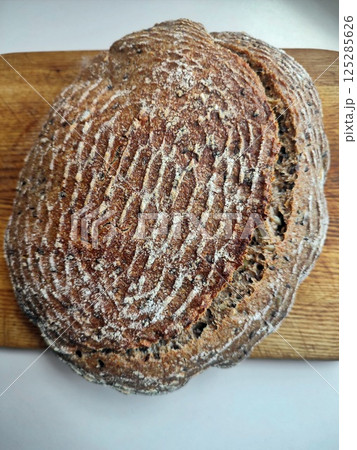 freshly baked artisanal whole wheat sourdough bread with rustic crust cooling on a wooden surface top down view 125285626