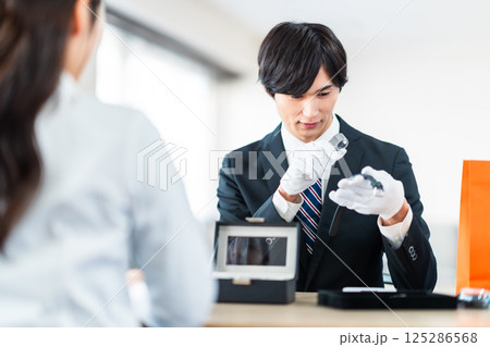 中古品の査定をする買取専門業者と店舗に不用品を持ちん込んだ主婦 125286568