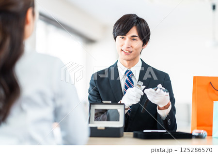 中古品の査定をする買取専門業者と店舗に不用品を持ちん込んだ主婦 125286570