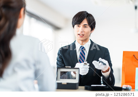 中古品の査定をする買取専門業者と店舗に不用品を持ちん込んだ主婦 125286571
