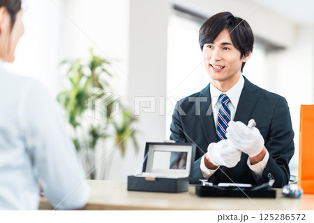 中古品の査定をする買取専門業者と店舗に不用品を持ちん込んだ主婦 125286572