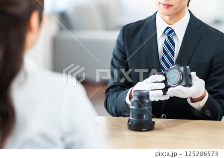 中古品の査定をする買取専門業者と店舗に不用品を持ちん込んだ主婦 125286573