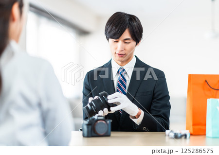 中古品の査定をする買取専門業者と店舗に不用品を持ちん込んだ主婦 125286575