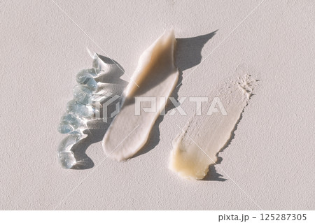 A set of different lotions and creams are spread out on a table. Texture of gel and serum on a light background. A set of different lotions and creams are spread out on a table. Texture of gel and serum on a light background. 125287305