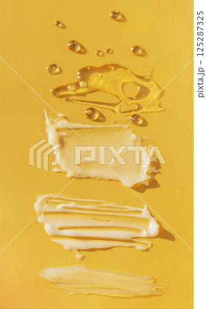 Different texture of gel and cream on a yellow background. Transparent and white serum with drops. The consistency of glycerin gel. Various smears of cream. Different texture of gel and cream on a yellow background. Transparent and white serum with drops. The consistency of glycerin gel. Various smears of cream. 125287325