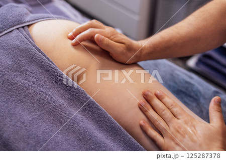 Masseuse makes anti cellulite massage of buttocks, thighs and legs to her client Masseuse makes anti cellulite massage of buttocks, thighs and legs to her client 125287378