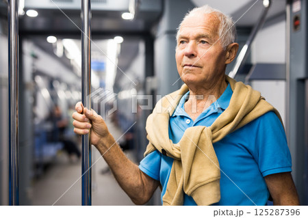 Old man standing in subway car Old man standing in subway car 125287396
