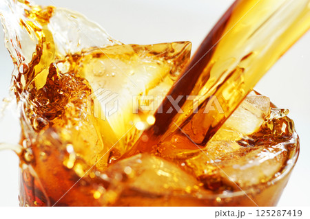 グラスに勢いよく注がれるアイスコーヒーとスプラッシュ グラスに勢いよく注がれるアイスコーヒーとスプラッシュ 125287419