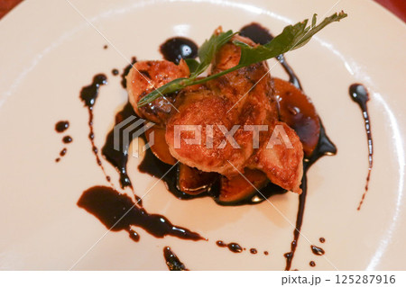 close up of Foie Gras with Caramelised Apple with black vinegar sauce on a white plate close up of Foie Gras with Caramelised Apple with black vinegar sauce on a white plate 125287916