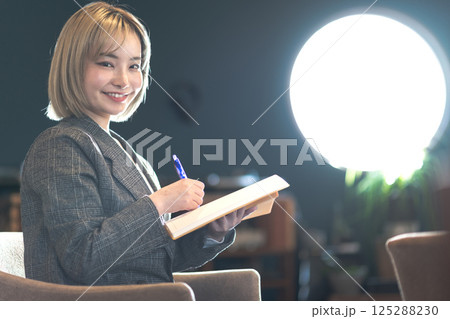 丸い窓の喫茶店でノートにメモを取る若い女性 丸い窓の喫茶店でノートにメモを取る若い女性 125288230