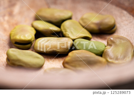 Dried Vicia faba or broad beans in wooden bowl close up 125289073