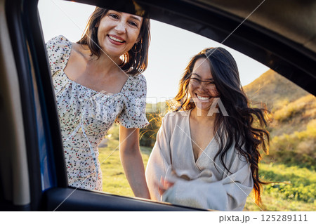 Young women of different races laugh and have fun together during the trip. View from the car window. 125289111