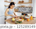 Young attractive Asian woman prepares delicious sandwich with fish and avocado 125289149