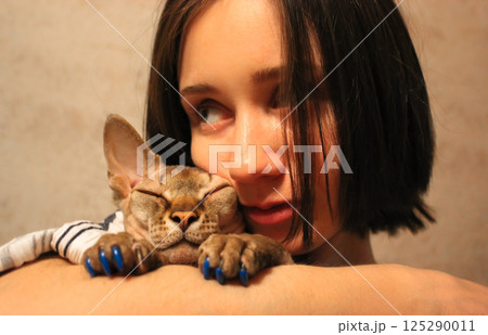 Beautiful woman cuddling hugging beloved bald Canadian Sphynx naked hairless cat 125290011