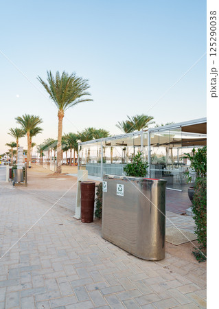 Clean and organized beachfront area with palm trees and dining spaces during early evening Clean and organized beachfront area with palm trees and dining spaces during early evening 125290038