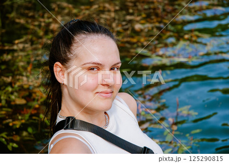 Serene outdoor portrait of a smiling woman by a lake in nature. Weekend concept near the forest and lake Serene outdoor portrait of a smiling woman by a lake in nature. Weekend concept near the forest and lake 125290815