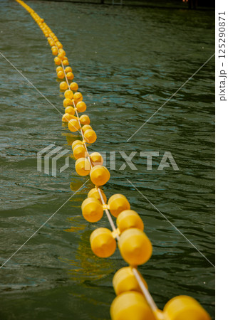 Bright yellow buoys floating in calm water with nautical theme for summer design. Weekend concept near the forest and lake Bright yellow buoys floating in calm water with nautical theme for summer design. Weekend concept near the forest and lake 125290871