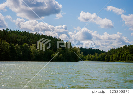 Scenic lakeside view with forest and cloudy sky in tranquil nature setting. Weekend concept near the forest and lake Scenic lakeside view with forest and cloudy sky in tranquil nature setting. Weekend concept near the forest and lake 125290873