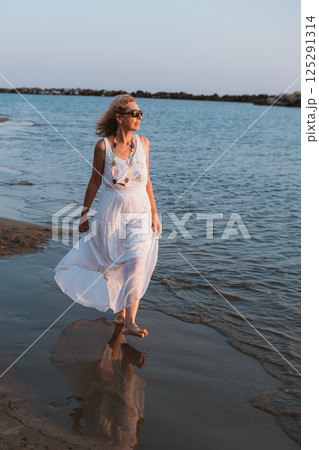 Woman Walking on the Beach in a White Dress 125291314