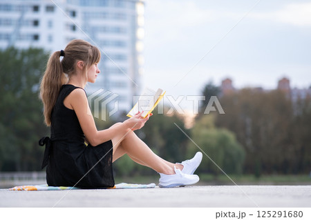 Young woman resting in summer park reading a book. Education and sudy concept. 125291680