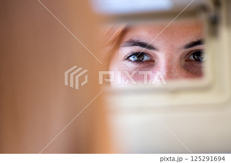 Young woman driver checking rear view mirror looking backwards while driving a car. 125291694