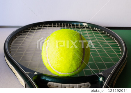 Close up of tennis racket strung and tennis ball Light background 125292054