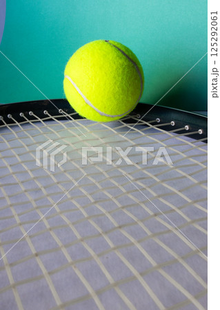 side view of a tennis racket strung in the foreground. Green background 125292061