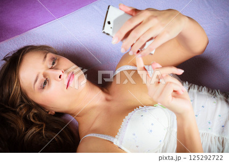 Lying girl holding smartphone. Lying girl holding smartphone. 125292722