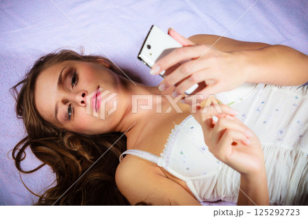 Lying girl holding smartphone. 125292723