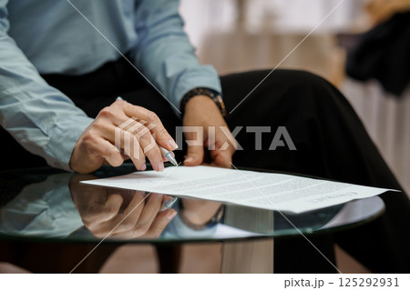 Professional Businessman Signing Important Document at Stylish Glass Table 125292931