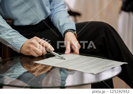 Professional Hand Holding Pen Over Document on Glass Table Professional Hand Holding Pen Over Document on Glass Table 125292932