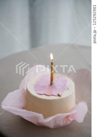 Simple Elegant Birthday Cake with a Single Candle on a Table 125292981
