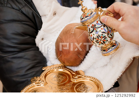 A Close-Up of an Infants Baptism Ceremony with Traditional Ornate Vessel and Tray 125292992