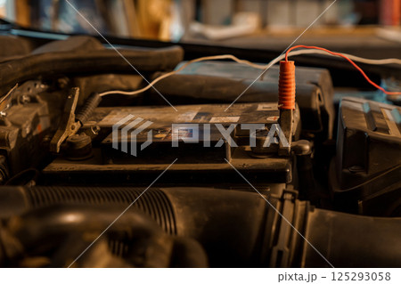 Close-Up of a Car Battery with Red Clamp and Wiring in an Automotive Workshop Close-Up of a Car Battery with Red Clamp and Wiring in an Automotive Workshop 125293058