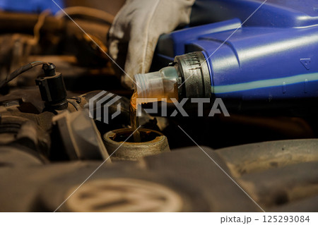 Pouring Engine Oil into a Car Engine for Maintenance 125293084