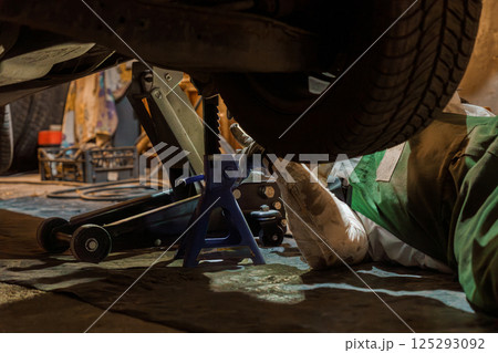 Mechanic Working Underneath Raised Vehicle with Jack 125293092