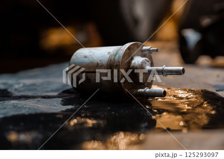 Rusty Fuel Filter on a Workshop Floor with Spill 125293097