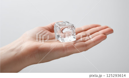 Hand Holding a Clear Ice Cube Against Light Background 125293614