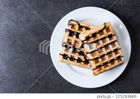 Belgian Waffles with chocolate on black slate background Belgian Waffles with chocolate on black slate background 125293660